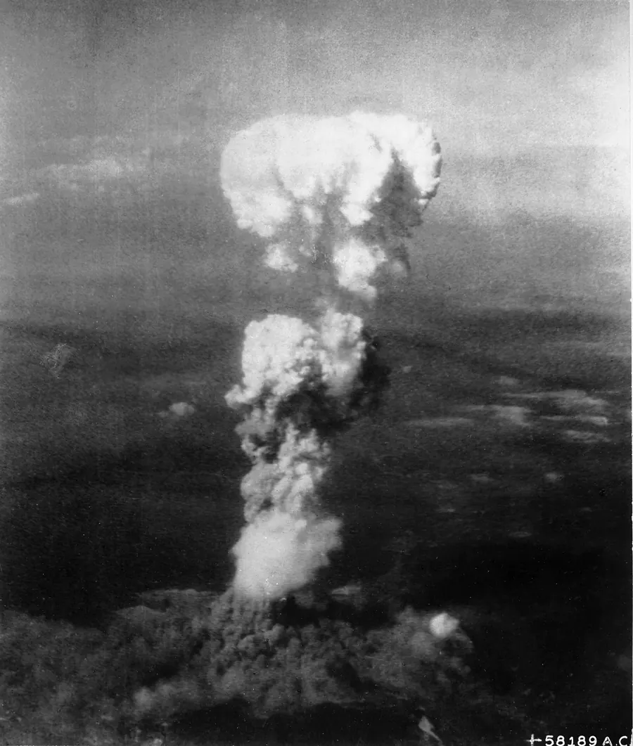 A tall grey mushroom cloud rising over the city of Hiroshima in 1945.