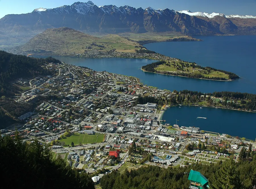 A town beside a blue lake below steep mountains near Queenstown, New Zealand.